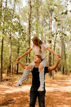 two people are playing with each other in the woods while one person holds on to his back