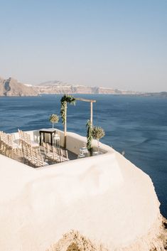 an outdoor dining area overlooking the ocean with chairs and tables set up on top of it