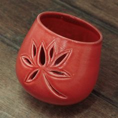 a red vase sitting on top of a wooden table