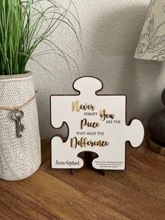 a white puzzle piece sitting on top of a wooden table next to a potted plant