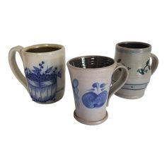 three coffee mugs sitting next to each other on a white surface with blue designs