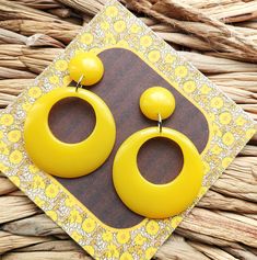 Retro 1950's Style Yellow Hoop Earrings. I have made these fabulous statement drop hoop earrings in resin, using retro yellow colouring. The drop hoops have a classic 1950's style and measure 42mm in diameter. They are fixed to the top studs which are 17mm in diameter and have a 6mm dome. They are finished with silver tone brass earring posts and have an total drop of 62mm. They are incredibly lightweight making them easy to wear. They will look amazing with your vintage dresses and also jeans a Vintage Yellow Resin Jewelry, Retro Yellow Earrings For Gifts, Lightweight Jewellery, Rockabilly Looks, Bold Statement Jewelry, 50s Rockabilly, Retro Yellow, Drop Hoop Earrings, 60s Style