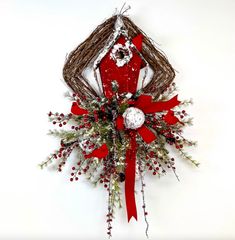 a christmas wreath hanging on the wall with red ribbon and decorations around it's edges