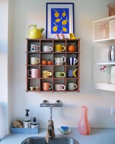 a shelf filled with cups and mugs on top of a kitchen counter next to a sink