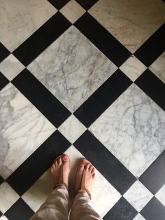 a person standing on top of a black and white checkered floor with their feet up