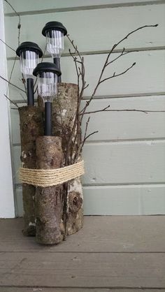 three lights are placed on top of a tree stump and tied to the side of a house