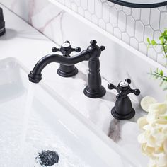 two black faucets sitting next to each other on a white counter top in front of a mirror