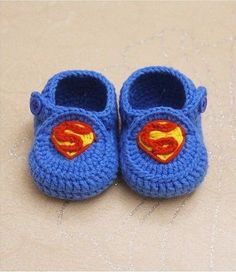 a pair of blue crocheted baby shoes with a superman symbol on the front