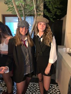 two girls dressed in school uniforms standing next to each other near a tree and tiled floor