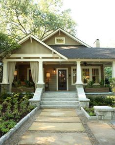 a house that is sitting in the middle of some bushes and trees with steps leading up to it