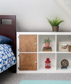 a white bookcase with wooden doors and drawers in a bedroom next to a bed