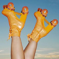 a woman's legs wearing yellow shoes with orange decorations on them and her feet in the air