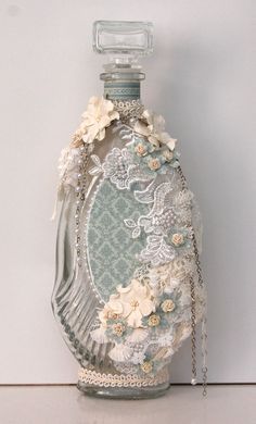 a glass bottle with lace and flowers on it