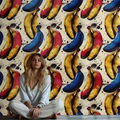 a woman sitting on the floor in front of a banana wallpaper