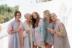 a group of women standing next to each other wearing robes and holding drinks in their hands