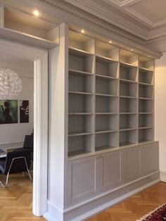 an empty bookcase in the middle of a room with hardwood floors and white walls