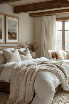 a large bed sitting in a bedroom next to a window covered in blankets and pillows