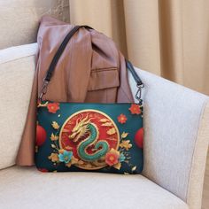 🐉Keep your style on point and your hands free with our Women's Versatile Crossbody Bag/Purse with a Gold, Teal & Red Mystical Dragon Design. It's made of premium faux leather and features dark gray hardware. Thanks to the zip-top closure and multiple inside pockets, you can keep your essentials secure and organized. Transform this crossbody bag with removable wrist and shoulder straps to style it for day-to-night looks. * Outer fabric: faux leather  * Lining: 100% polyester * 11″ × 8″ × 1.5″ (27.9 cm × 20.3 cm × 3.8 cm) * Dark gray hardware * Zip-top closure * Inside zip and slip pockets * Adjustable, removable wrist and shoulder straps * Strap drop length: 14″- 27″ Red Handheld Portable Shoulder Bag, Red Portable Handheld Shoulder Bag, Handheld Bags As Gifts, Handheld Portable Bags As Gifts, Portable Handheld Bags For Gifts, Red Bag With Zipper Pouch As Gift, Portable Crossbody Bag, Handheld Mobile Phone Bag As Gift, Red Portable Bag For Daily Use