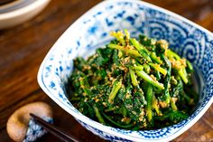 a blue and white bowl filled with broccoli on top of a wooden table