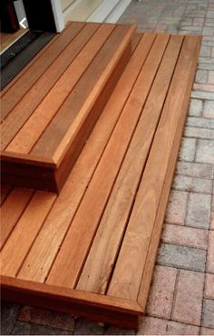 a wooden bench sitting on the side of a brick road next to a door and window