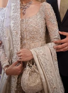 a man and woman standing next to each other in formal wear, one wearing a veil