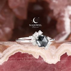 a black diamond ring sitting on top of a piece of rock next to a moon