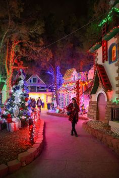 a woman walking down a street covered in christmas lights