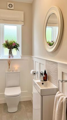 a white toilet sitting next to a sink in a bathroom under a window with a potted plant on top of it