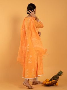 Set of 3 consists of kurta, pants, and dupatta. A summer bright orange kurta enriched with white khari print set on a light cotton base Kurta: Kalidar kurta with white khari print flowers, 3/4th sleeves and contrast white lace detailing on hemline, neckline and sleeves Dupatta: Handspun kota doria dupatta in orange and white, adorned with tassels and khari print Pants: Narrow ivory cotton pants with scallop lace edging. Fit: Relaxed & straight fit Wash Care Instructions: Dry Clean Only Note: Orange Kurta With Cutdana For Eid, Orange Cutdana Kurta For Eid, Orange Chikankari Embroidery Palazzo Set For Diwali, Diwali Orange Chikankari Embroidery Palazzo Set, Traditional Orange Palazzo Set With Straight Kurta, Orange Kurta With Sheer Dupatta For Navratri, Orange Anarkali Set With Dupatta And Straight Kurta, Bollywood Style Orange Palazzo Set With Straight Kurta, Orange Printed Motifs Palazzo Set