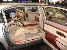 the interior of a car with its doors open and people standing around looking at it