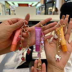 four different colored lip glosses being held by two hands