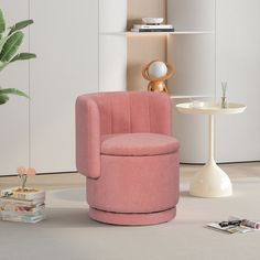 a pink chair sitting next to a white table in a living room with a potted plant on the floor