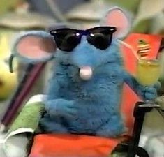 a blue stuffed mouse wearing sunglasses and holding a drink in it's hand while sitting on an orange chair