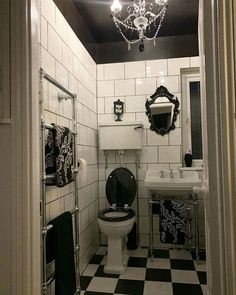 a black and white tiled bathroom with chandelier above the toilet, sink and mirror