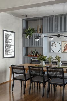 a dining room table with six chairs in front of it and shelves on the wall