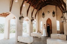 a bride and groom standing in the doorway of a church with stone benches on each side