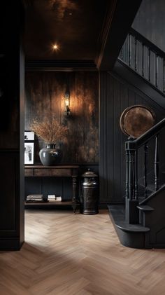 an empty room with wooden floors and dark wood walls, along with a staircase leading up to the second floor