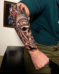 a man with a black and grey tattoo on his arm wearing a headdress