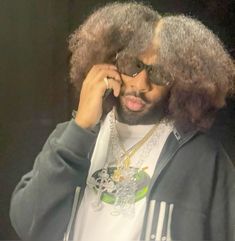 the man is talking on his cell phone while wearing glasses and a jacket with an afro wig