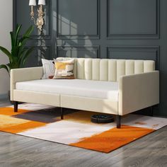 a white couch sitting on top of a wooden floor next to a lamp and rug