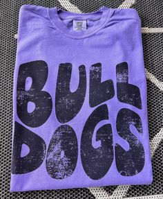 Here's a tee made just for you and your team spirit! This distressed BULLDOGS Mascot tee is super soft and comfy. Shown on a super soft comfort colors VIOLET tee, but so many colors to choose from. Design made on unisex comfort colors shirt. Purple Fan Apparel T-shirt With Letter Print, Relaxed Fit Logo Print T-shirt For Fan Merchandise, Casual Cotton T-shirt For Game Day, Casual Text Print T-shirt For Fan Gear, Relaxed Fit T-shirt With Logo For Fans, Sporty Relaxed Fit T-shirt For Fan Gear, Team Spirit Relaxed Fit T-shirt With Logo, Team-colored Text Print T-shirt For Streetwear, Relaxed Fit Team Spirit T-shirt With Logo Print