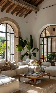 a living room filled with lots of white furniture and large arched windows on the wall