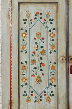 the door is decorated with colorful flowers and leaves on white painted wooden paneled doors