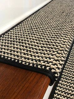 a black and white rug sitting on top of a wooden floor next to a wall