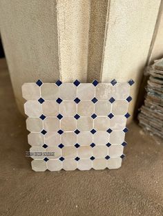 a white and blue mosaic tile on the floor next to a stack of stacked tiles