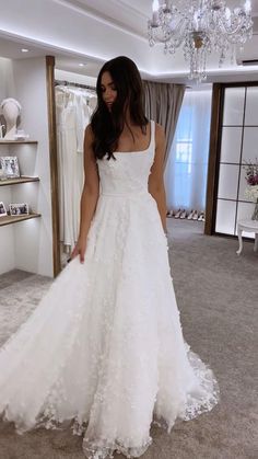 a woman standing in front of a mirror wearing a wedding dress