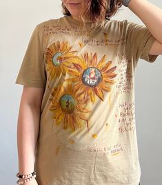 a woman wearing a brown shirt with sunflowers painted on it's chest