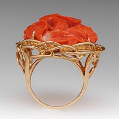 This fantastic vintage ring is centered with a carved floral design coral that is set into four-prongs. The coral is bordered with four (4) prong set round brilliant cut diamonds. The ring measures 25.9mm at the top, rises 12.7mm above the finger, tapering to 2.5mm wide and 0.8mm thick at the base of the shank. It is currently a size 4.5. Elegant Coral Ring Jewelry, Elegant Coral Rings For Anniversary, Coral Elegant Wedding Rings, Elegant Coral Wedding Rings, Elegant Carved Orange Jewelry, Elegant Orange Carved Jewelry, Coral Ring, Mid Century Jewelry, The Coral