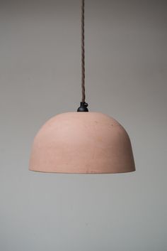 a light that is hanging from a rope on the ceiling with a gray wall in the background