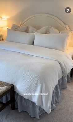 a bed with white sheets and pillows in a bedroom